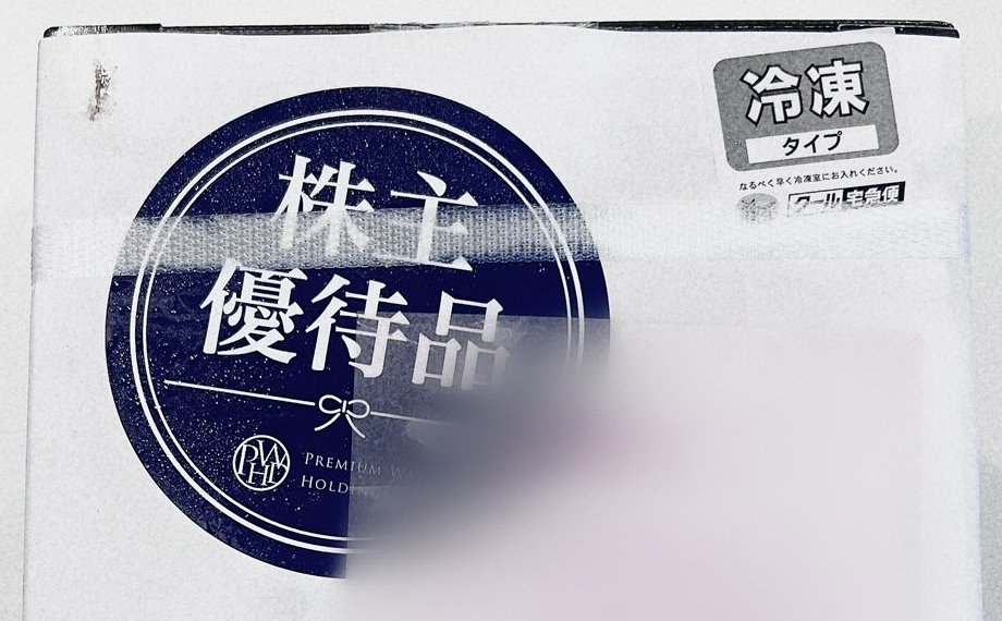 株主優待品の丸いシールと冷凍タイプの札が貼られた白い段ボール