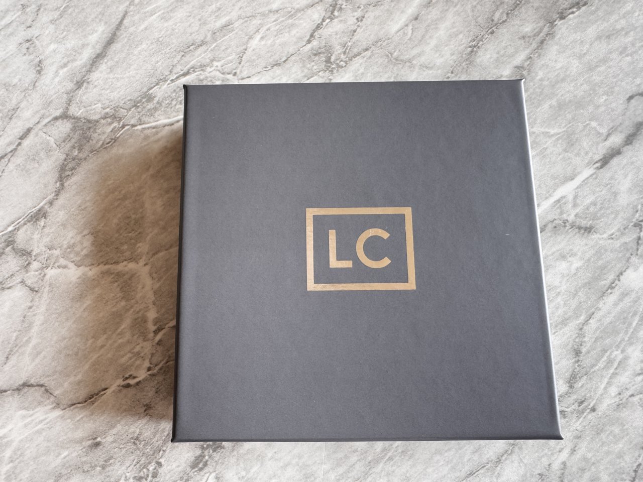 ラグジュアリーカードの濃いグレーの箱。ふたの中央に金色のLCのロゴ
