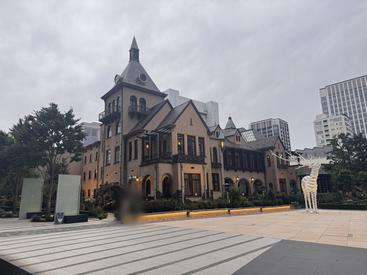 赤坂プリンス クラシックハウスの洋館の外観。尖塔のある建物とバラの植え込み、白い鹿の像
