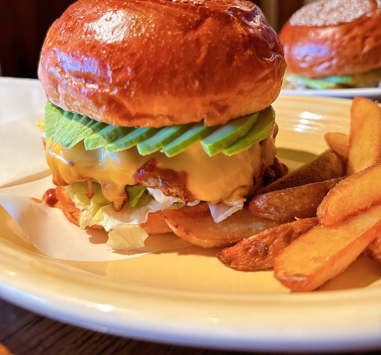 コーディーズのハンバーガー。つやのあるゴマのバンズの下にアボカドのスライスととろけたチーズ、レタスが重なり、横に皮付きのポテト