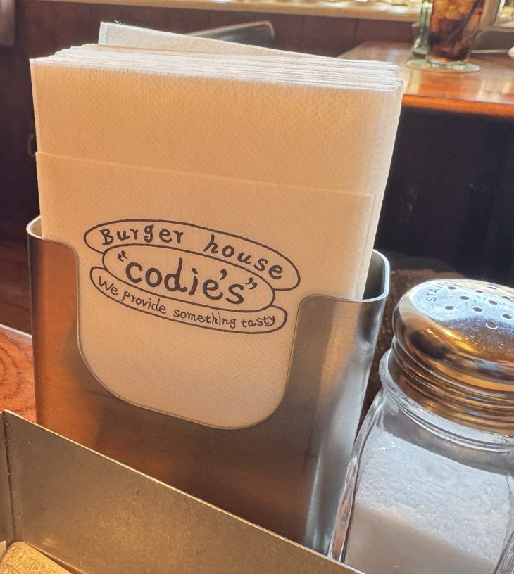 紙ナプキンに印刷されたBurger house codie's We provide something tastyのロゴ。横に塩の瓶