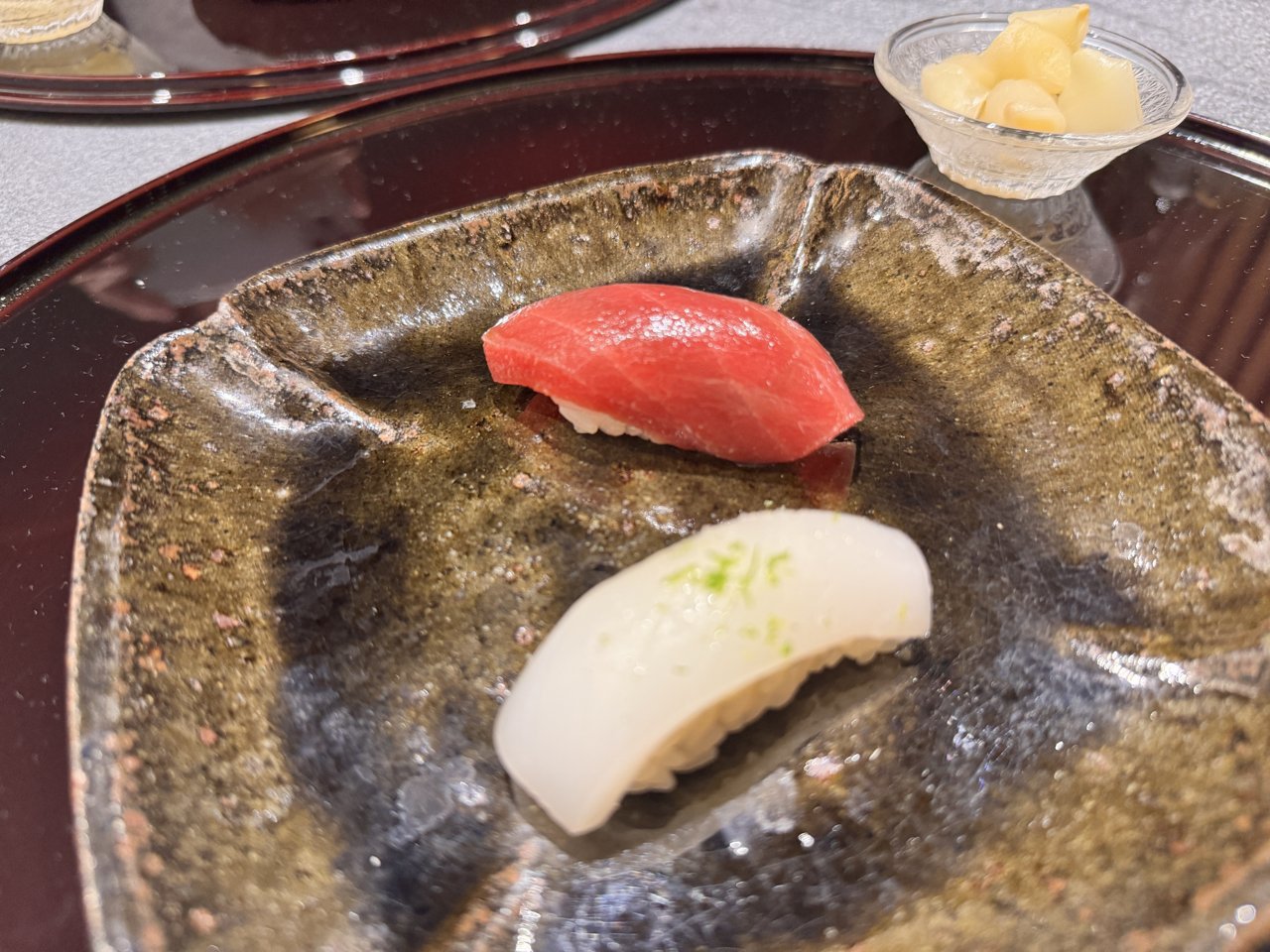 焼き物の皿にのったマグロとイカのにぎり二貫