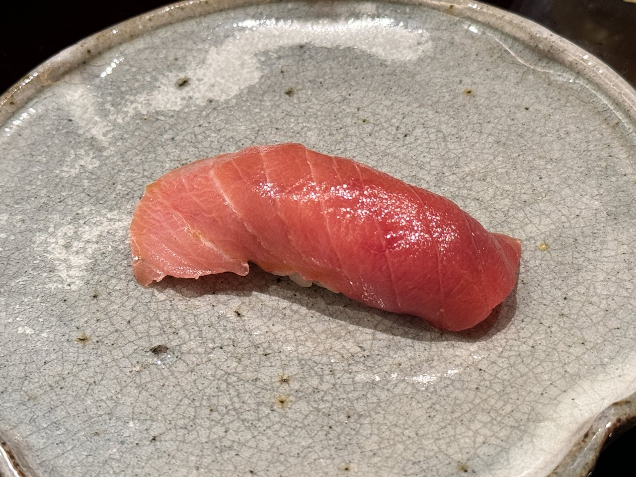 灰色の焼き物の皿にのったマグロのにぎり一貫