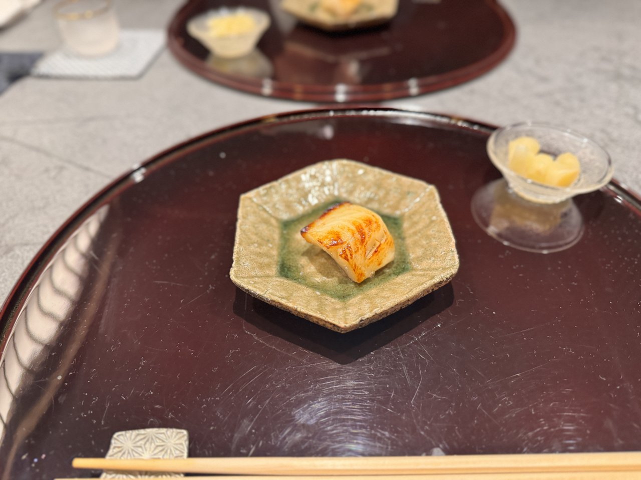 六角形の焼き物の皿にのった焼き目のついた白身の魚