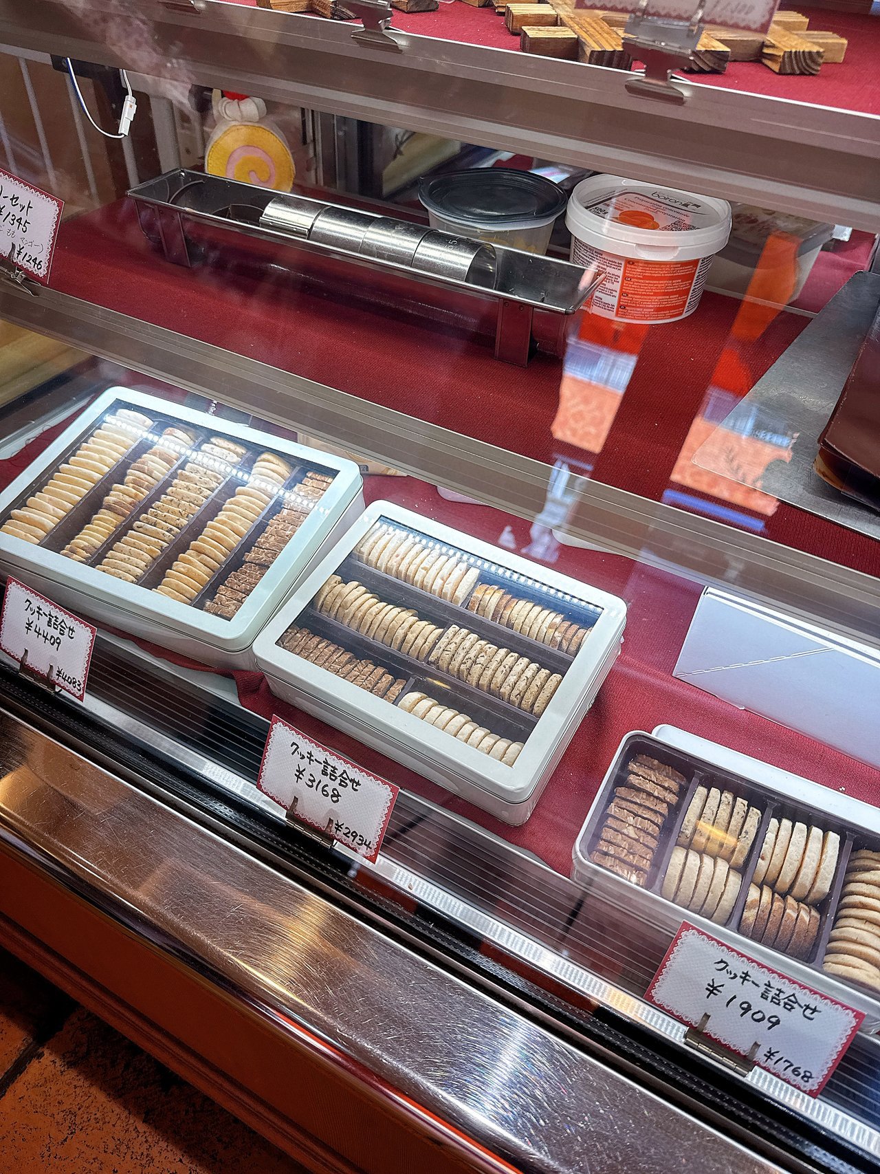 白い缶に入ったクッキー詰合せが3種類並ぶショーケース