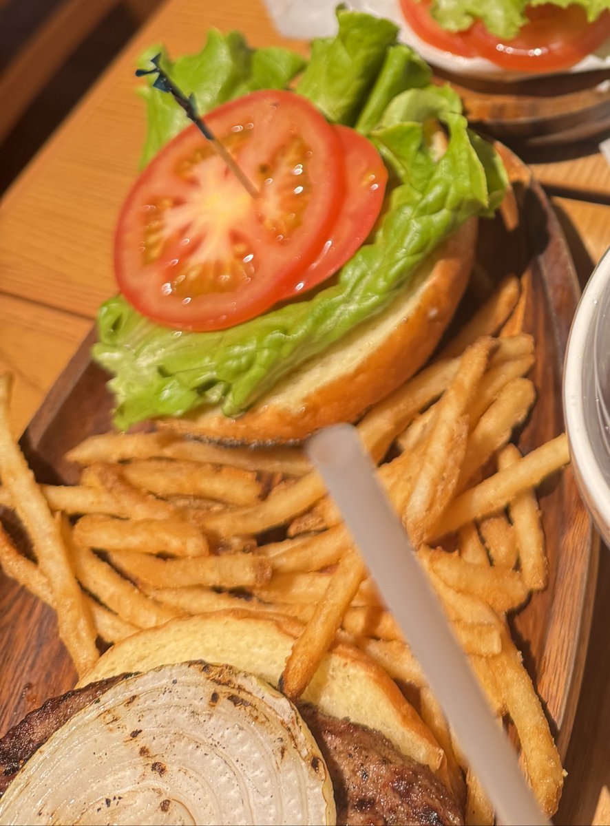 上のバンズにレタスと輪切りのトマトを別に盛ったハンバーガー。下のバンズにはパティとグリルした玉ねぎ、横に細いポテト