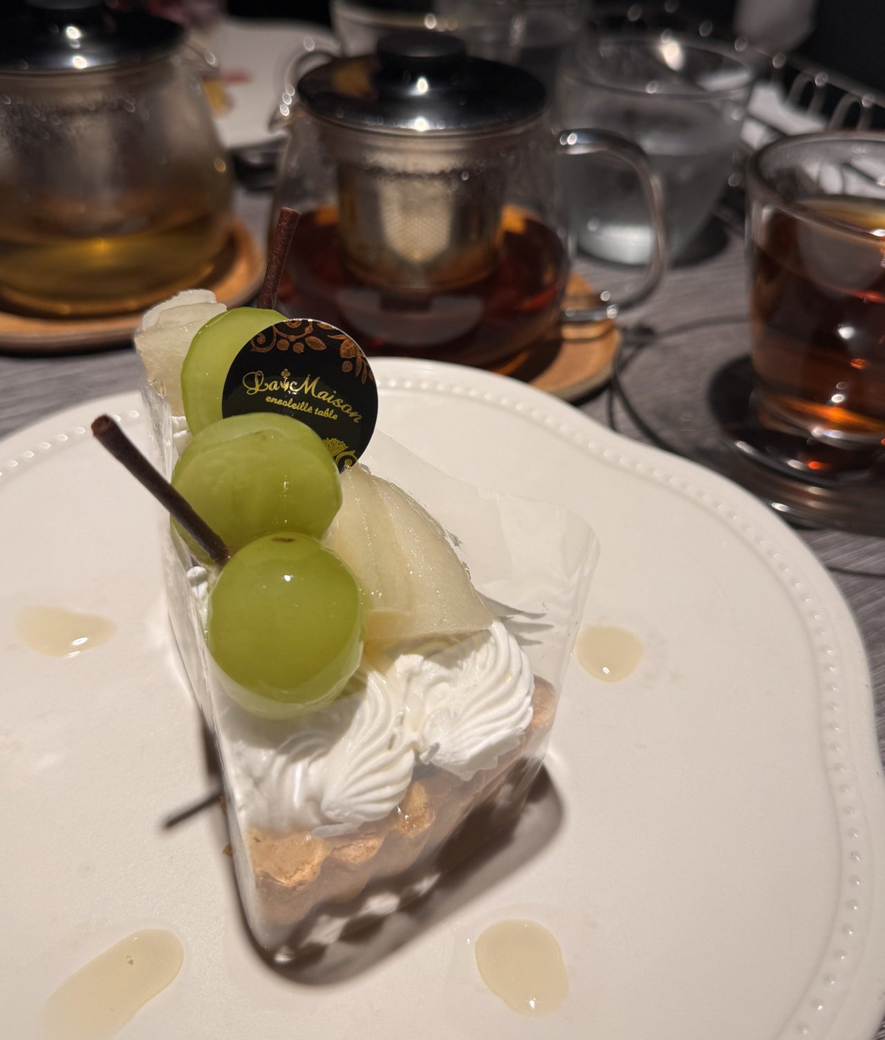 ラ・メゾン アンソレイユターブルのケーキ。上に緑のぶどう3粒と梨がのっている