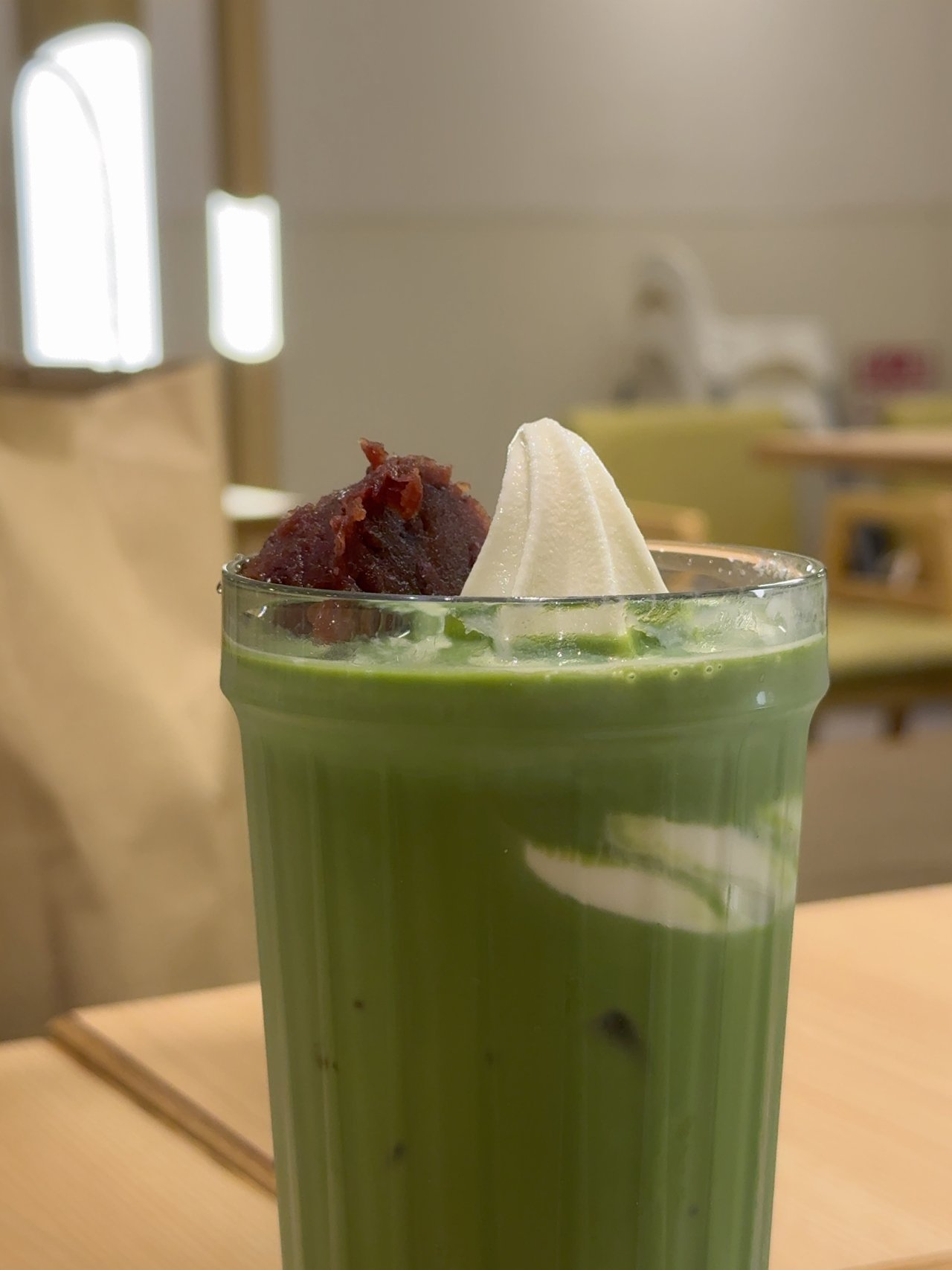 グラスの抹茶ラテの上に粒あんと白いソフトクリームがのっている