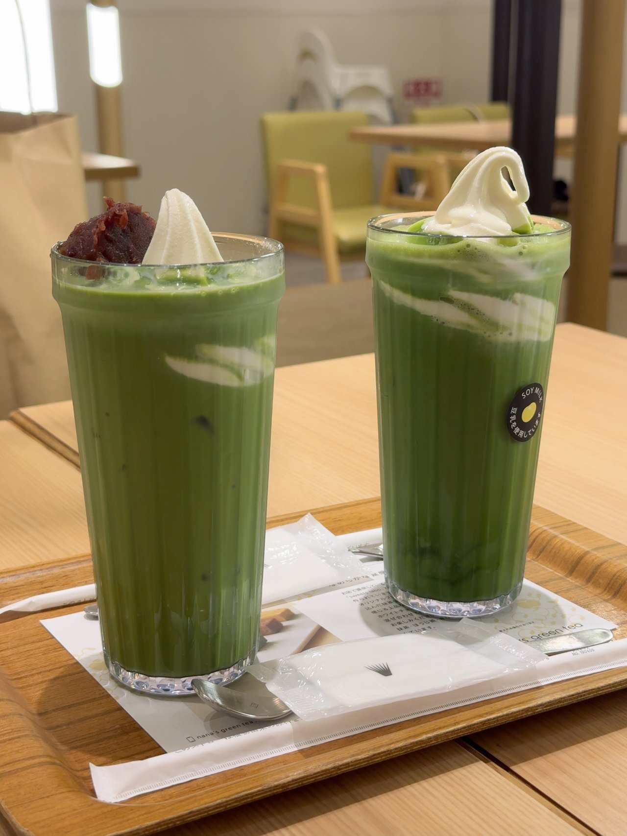 ナナズグリーンティーの木目のトレーにのった抹茶ラテ2杯。左は粒あんとソフトクリーム、右はソフトクリームがのっている