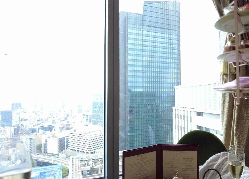 シャングリ・ラ 東京のラウンジの窓から見た高層ビルと首都高。右に3段のスタンドとメニュー冊子