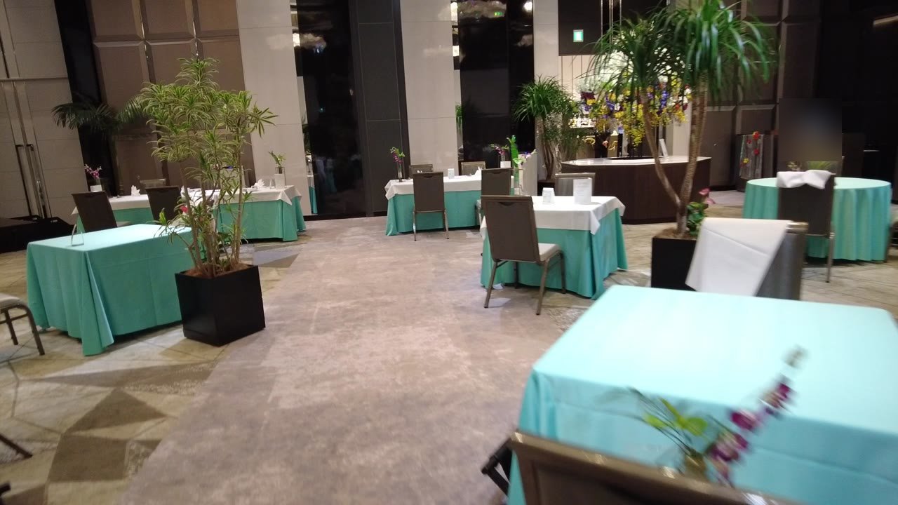ビュッフェの会場。ターコイズと白のクロスのテーブルと鉢植えが並ぶ
